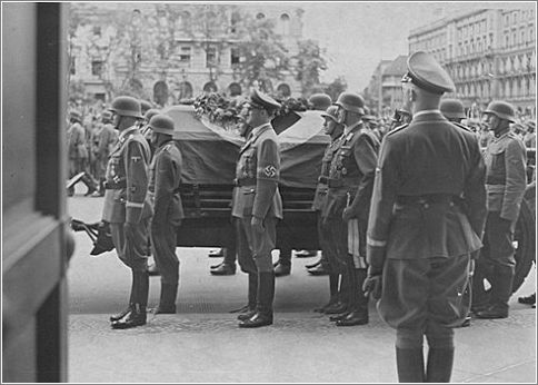 Reichsfuehrer-SS Heinrich Himmler looks on as Reinhard Heydrich's casket is carried out from the Reich chancellery for burial.